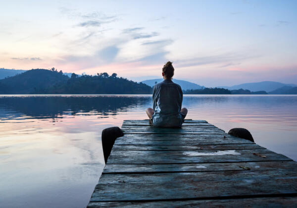 Peaceful,lifestyle,shot,of,woman,sitting,on,dock,at,sunset