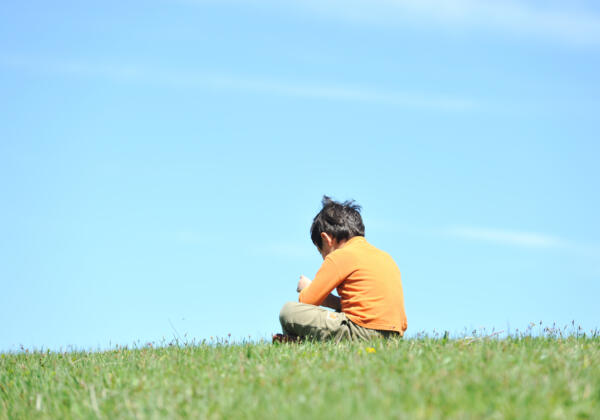 Photo,of,young,boy,sitting,on,the,grass,and,looking